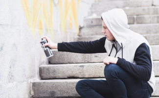 Un muchacho realiza una pintada ilegal sobre una pared. ¿Vandalismo o arte? 