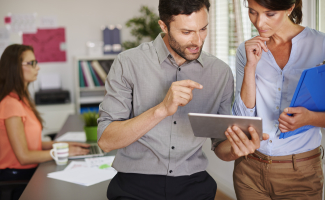 Una pareja de jóvenes administradores de fincas trabajan juntos con medios digitales.